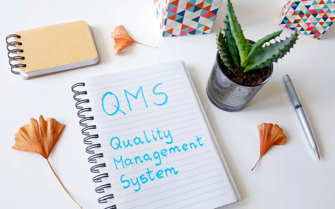 Cahier de notes ouvert avec écrit au fluo bleu Quality Management System (QMS)