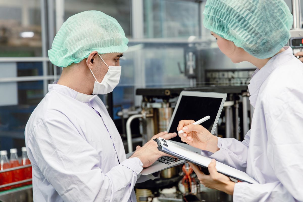 cplus-norme-iso-22000 Un homme et une femme qui font un contrôle qualité dans une usine alimentaire