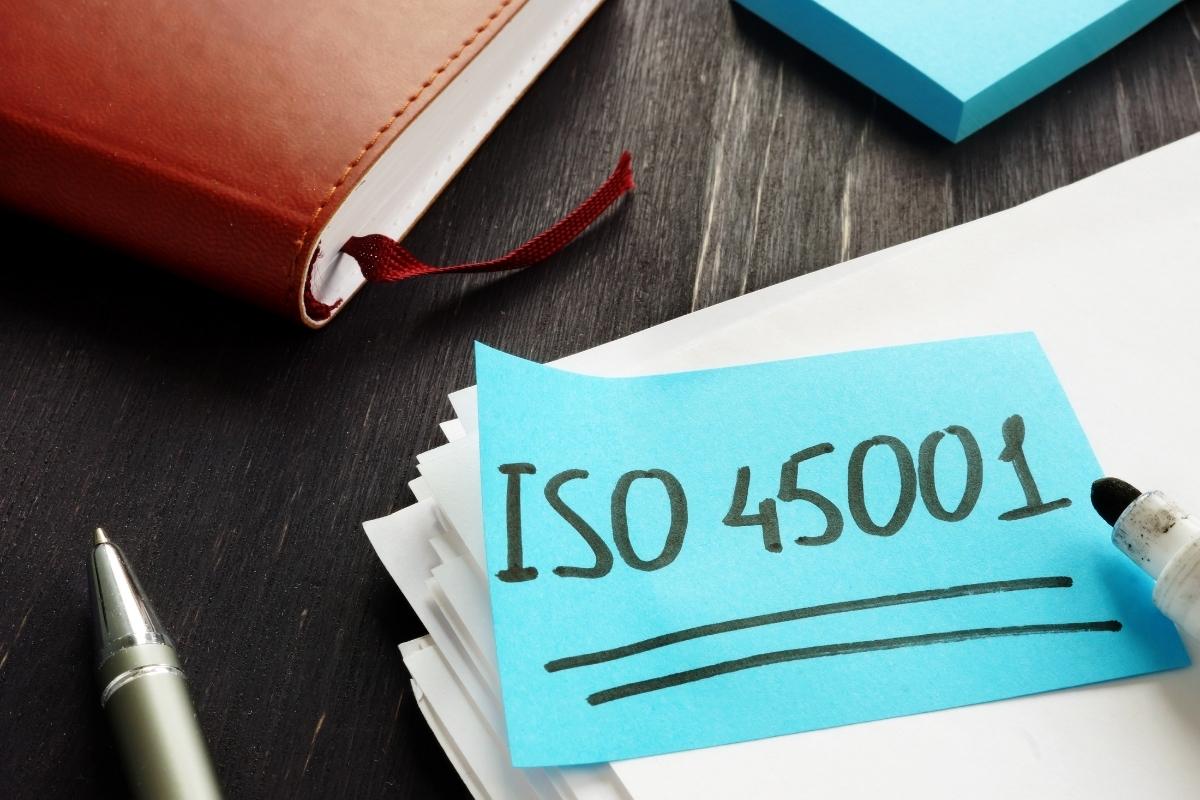 Post-il bleu sur un bureau en bois foncé avec ISO 45001 écrit au marqueur noir
