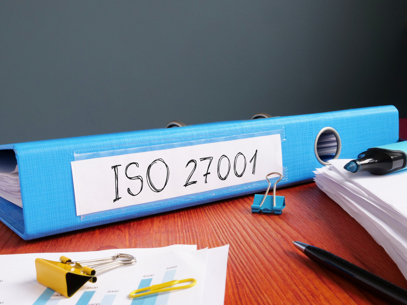 Farde bleue posée sur un bureau et sur laquelle est écrit "ISO 27001"